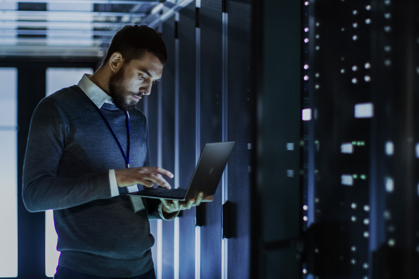 Man on laptop in dark server room