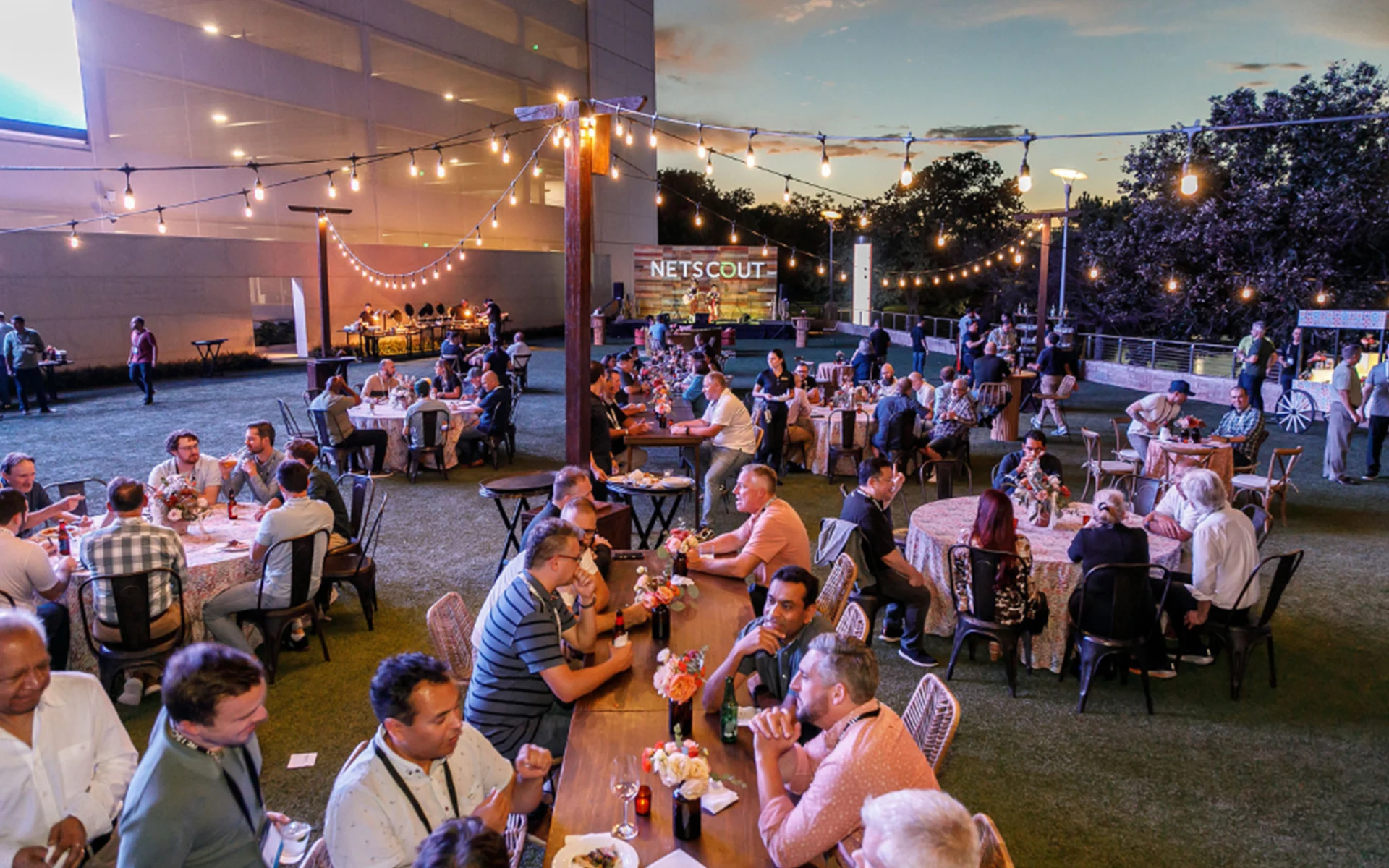 Outdoor venue with people mingling and sitting at tables