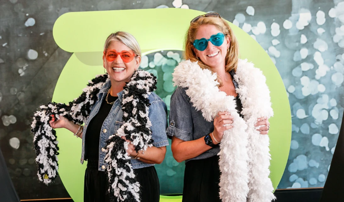 Two women wearing party boas and sunglasses