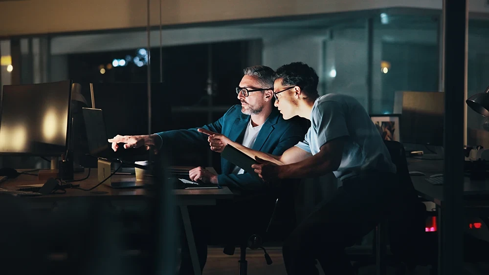 Two people working at a desk in a dark room