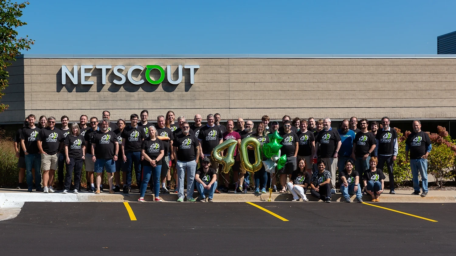 Large group of NETSCOUT employees standing in parking lot smiling at camera