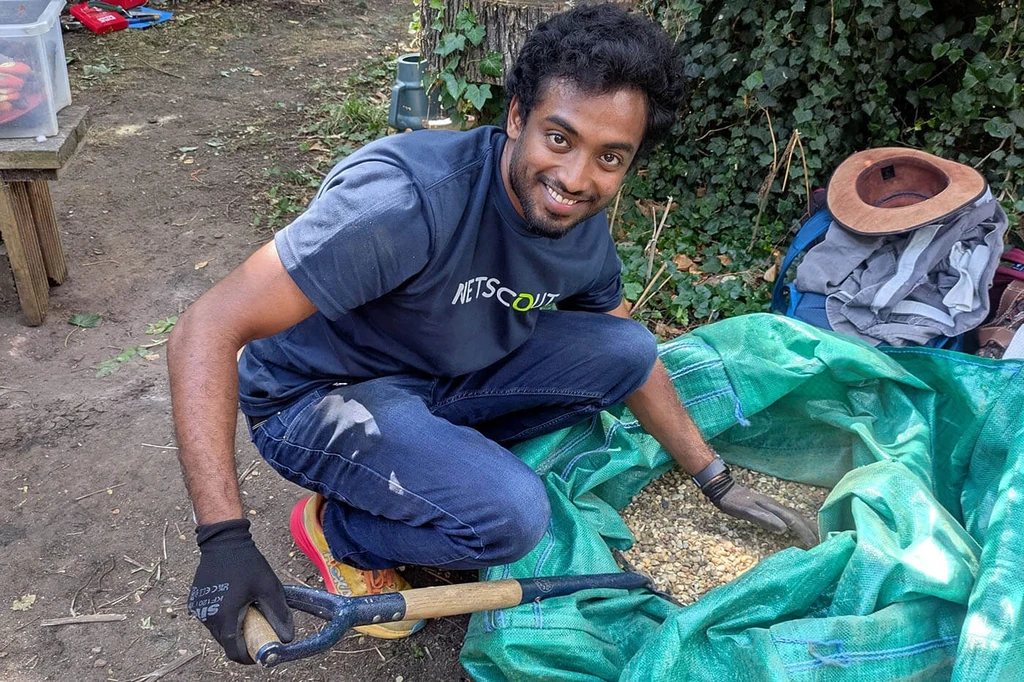 NETSCOUT employee shoveling gravel from bag outdoors