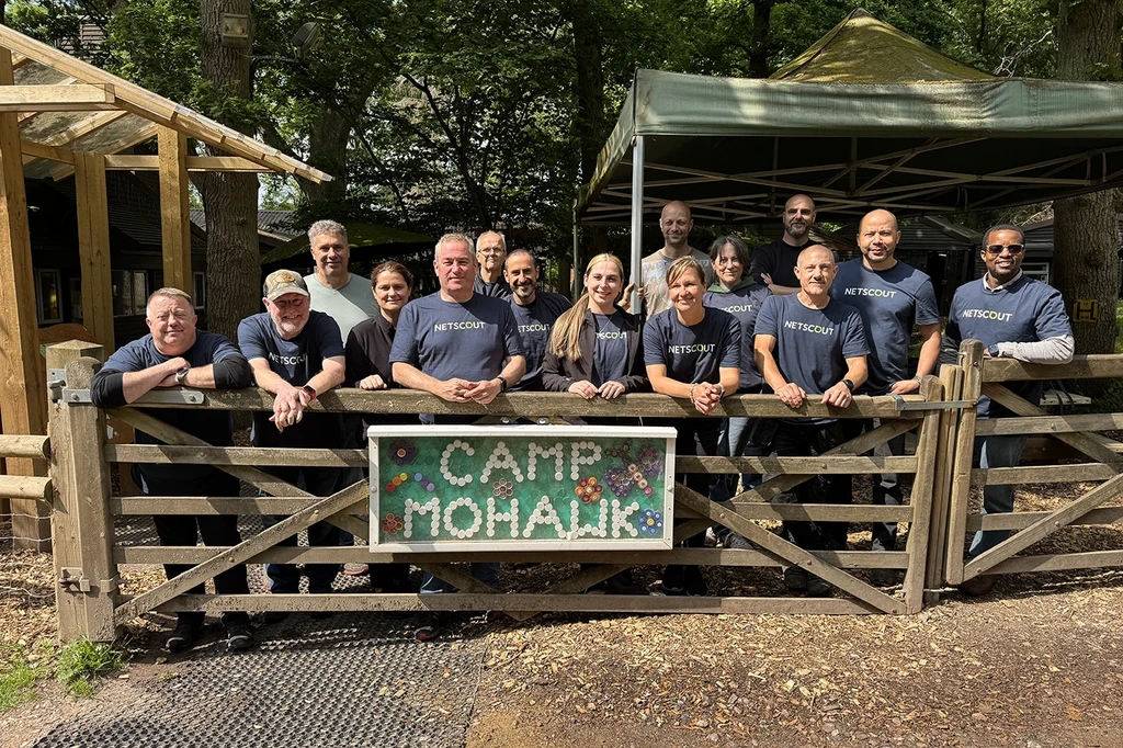 Group of NETSCOUT Employees at outdoor cabin site with Camp Mohawk sign