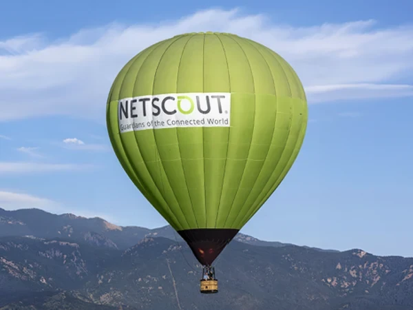 Green NETSCOUT hot air balloon over mountains in Colorado