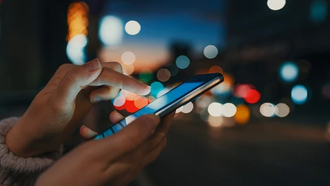 Hands holding a phone at night on a city street