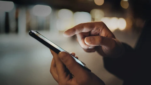 Hands holding a phone at night on a city street