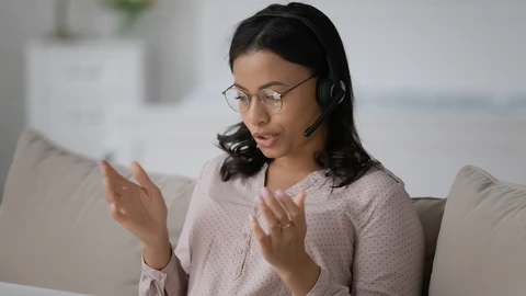 Woman with black hair sitting on couch talking on headset