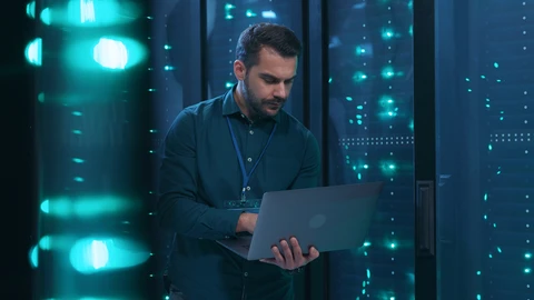 Man in server room holding laptop