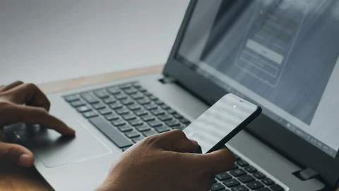 Hand with a cellphone and computer
