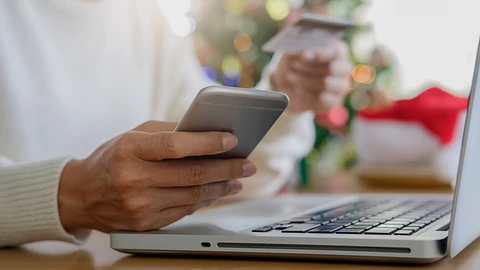 Person with cellphone, credit card and laptop