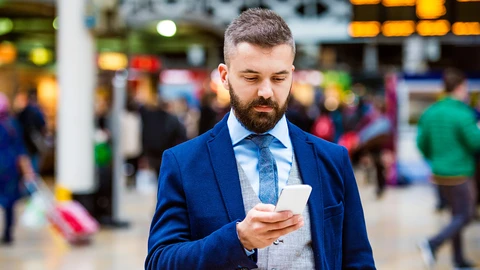 Man in suit looking at this cell phone while in a venue