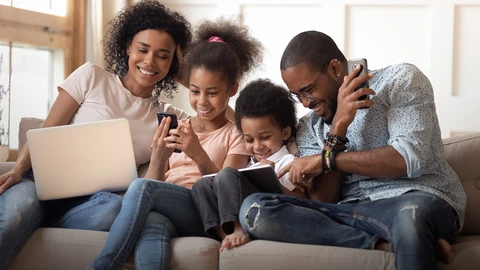 Family on sofa using Laptop, phones and tablet