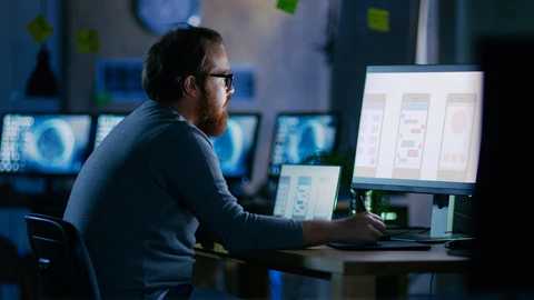 Man with glasses sitting at monitor in a NOC Lab.