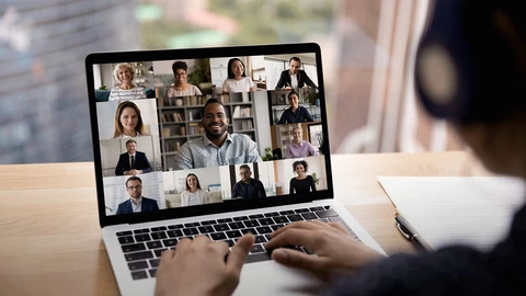Person on Laptop attending online meeting with 12 other people on screen using video