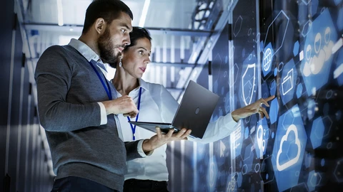  Man and woman viewing laptop and security items on a cloud system wall