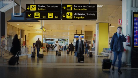 People walking with suitcases on phones in airport terminal
