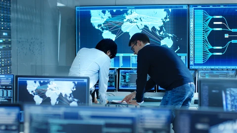 2 Men reviewing the cost savings over a laptop in a NOC.