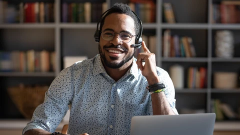 Male smiling with headset on in front of laptop