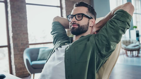 IT Worker sitting in chair with arms crossed behind his head.