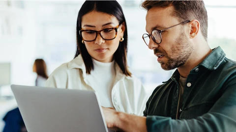 Co-workers reviewing issue reports on laptop
