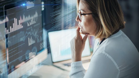 Woman IT person reviewing data on monitors