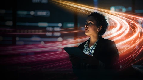 woman holding tablet looking up at server room with light swirls