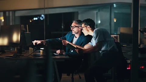 Two people working at a desk in a dark room