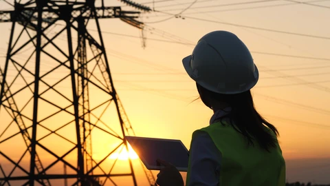 Electrical Utility Worker Standing in Front of Power Lines