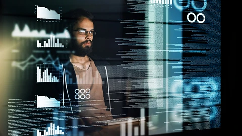Man in glasses working on computer with dashboard imposed in front of him