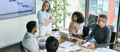 Professionals in a boardroom overlooking presentation on large screen