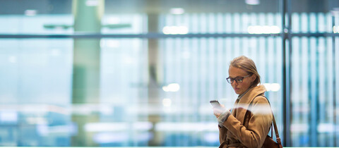Woman looking at mobile device on a moving walkway at airport