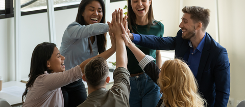 Employees standing in circle giving high five together