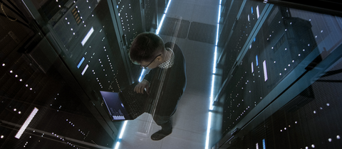 man on laptop in datacenter
