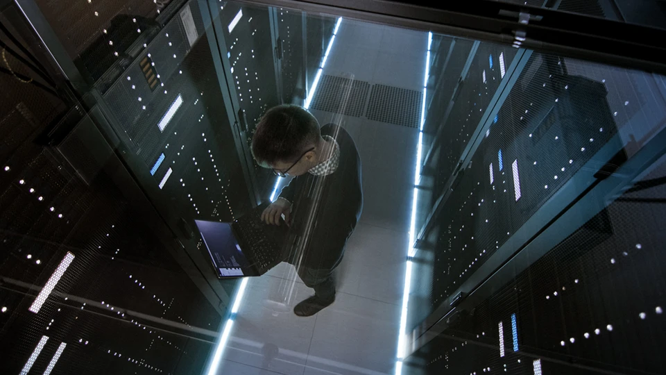 man on laptop in datacenter