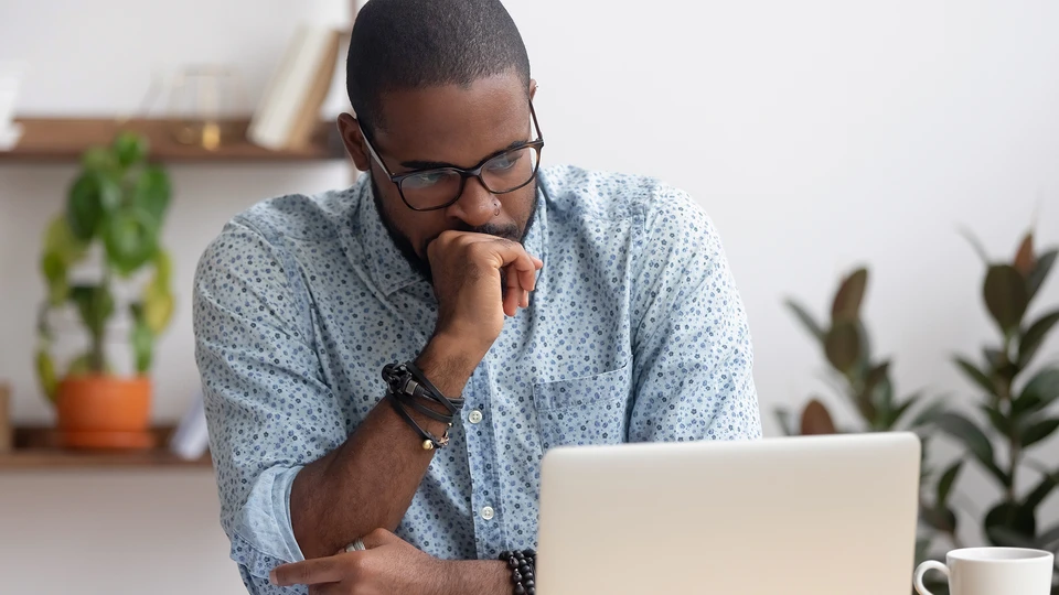 Man with hand on his chin in shape of a fist looking at laptop