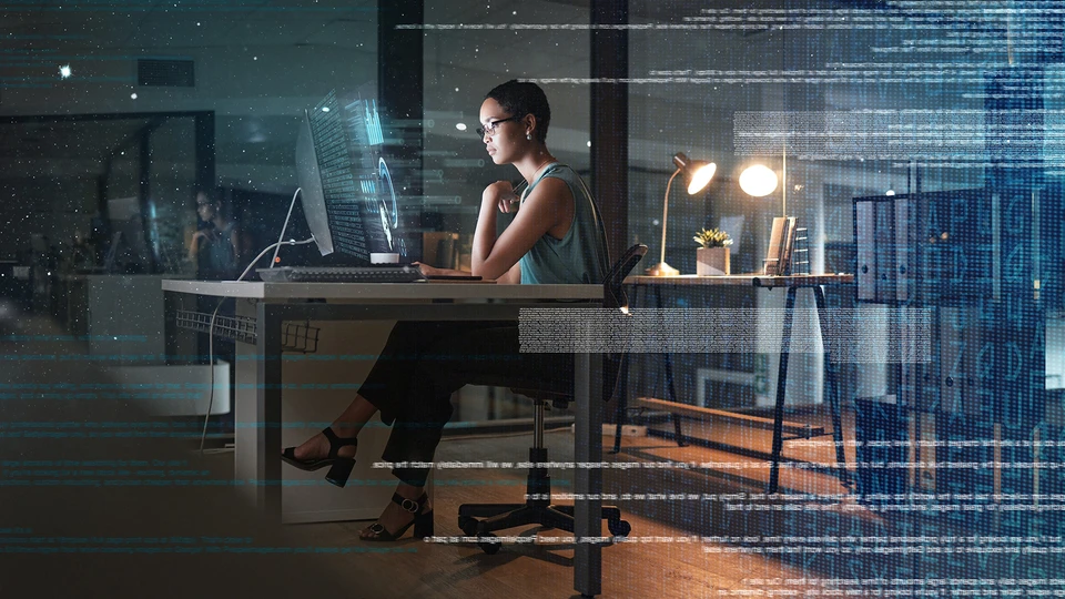person sitting at desk at night in a glass conference room